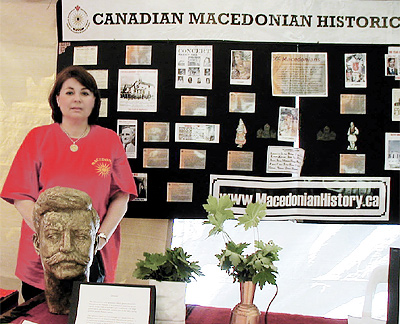 Жена покрај изложба на документи на Canadian Macedonian Historical Society, со натпис MacedonianHistory.ca